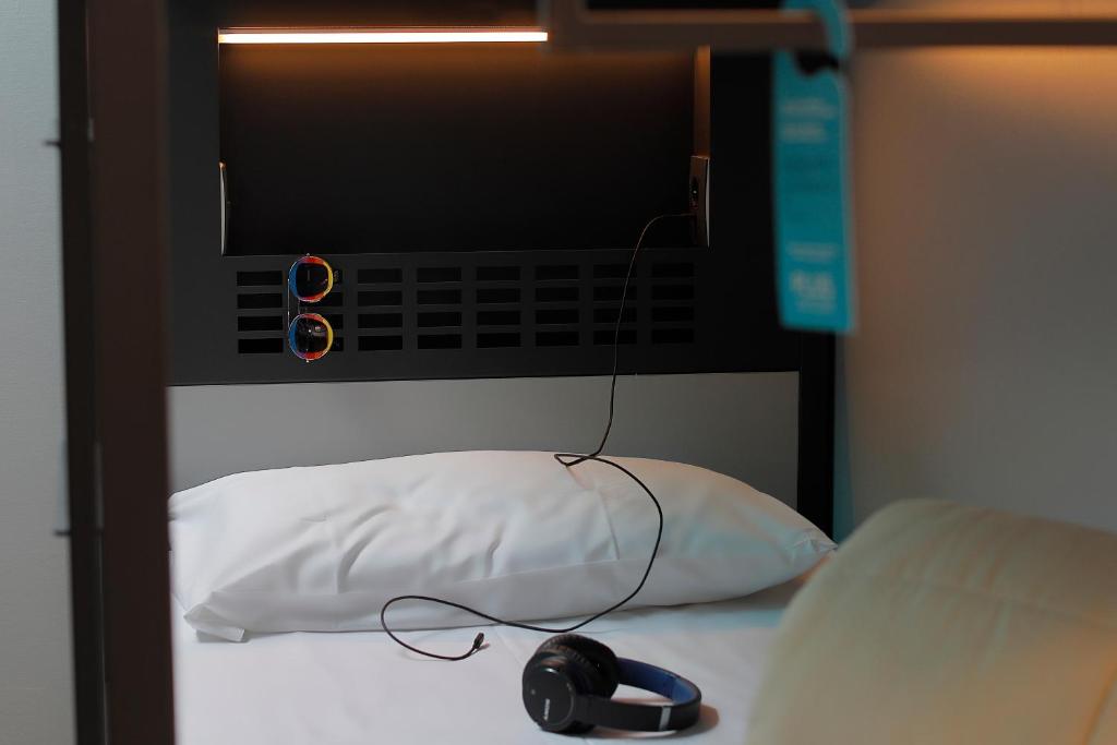 a computer monitor on a bed with a mouse on a pillow at Plus Florence in Florence