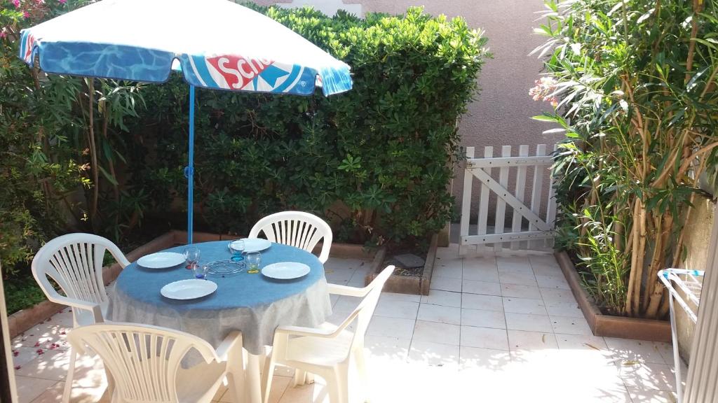 - une table avec un parasol et des chaises blanches dans l'établissement LES AMANDINES, au Cap d'Agde