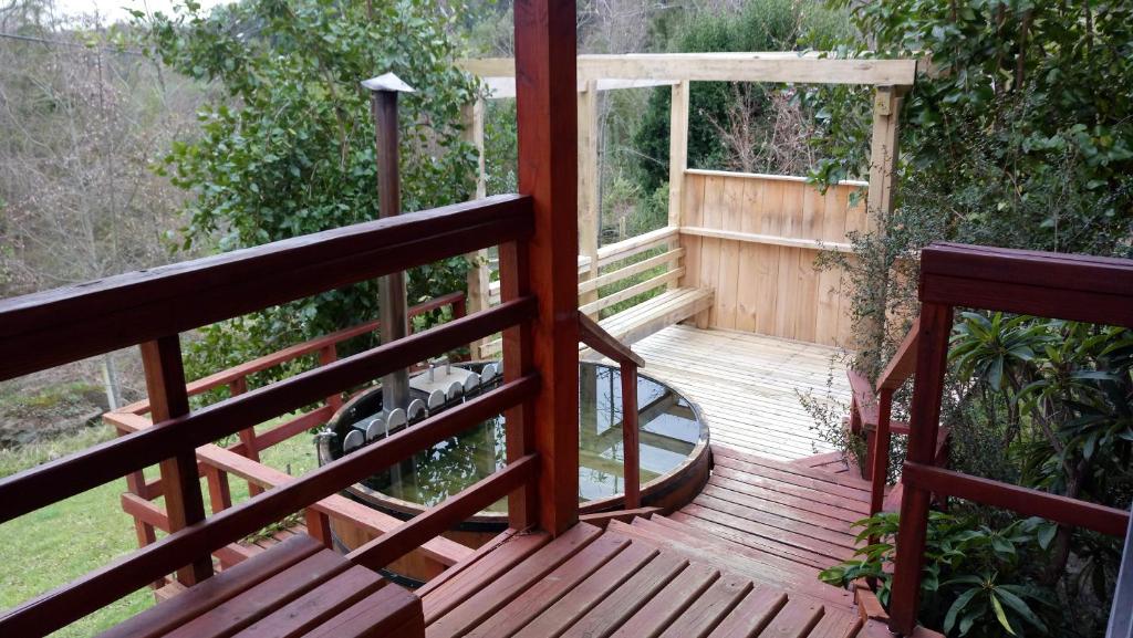 una terraza de madera con vistas al jardín en Cabaa Oregn con hot tub exclusivo cerca de termas y lago, en Coñaripe