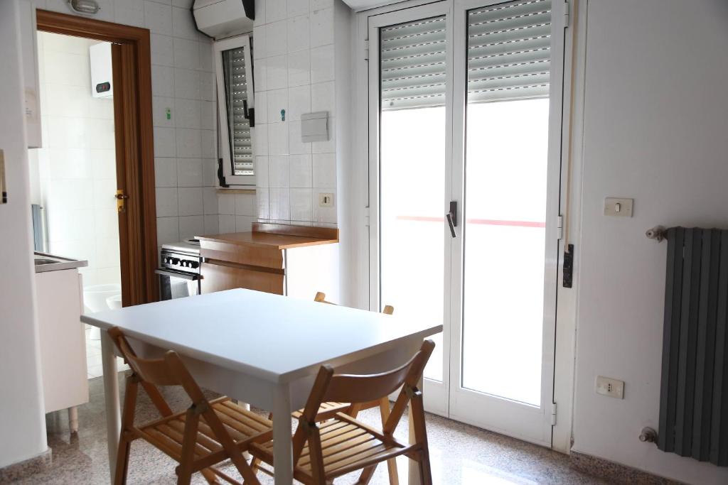 cocina con mesa blanca y sillas en una habitación en CENTRALISSIMO MINI APPARTAMENTO 1° piano en Margherita di Savoia
