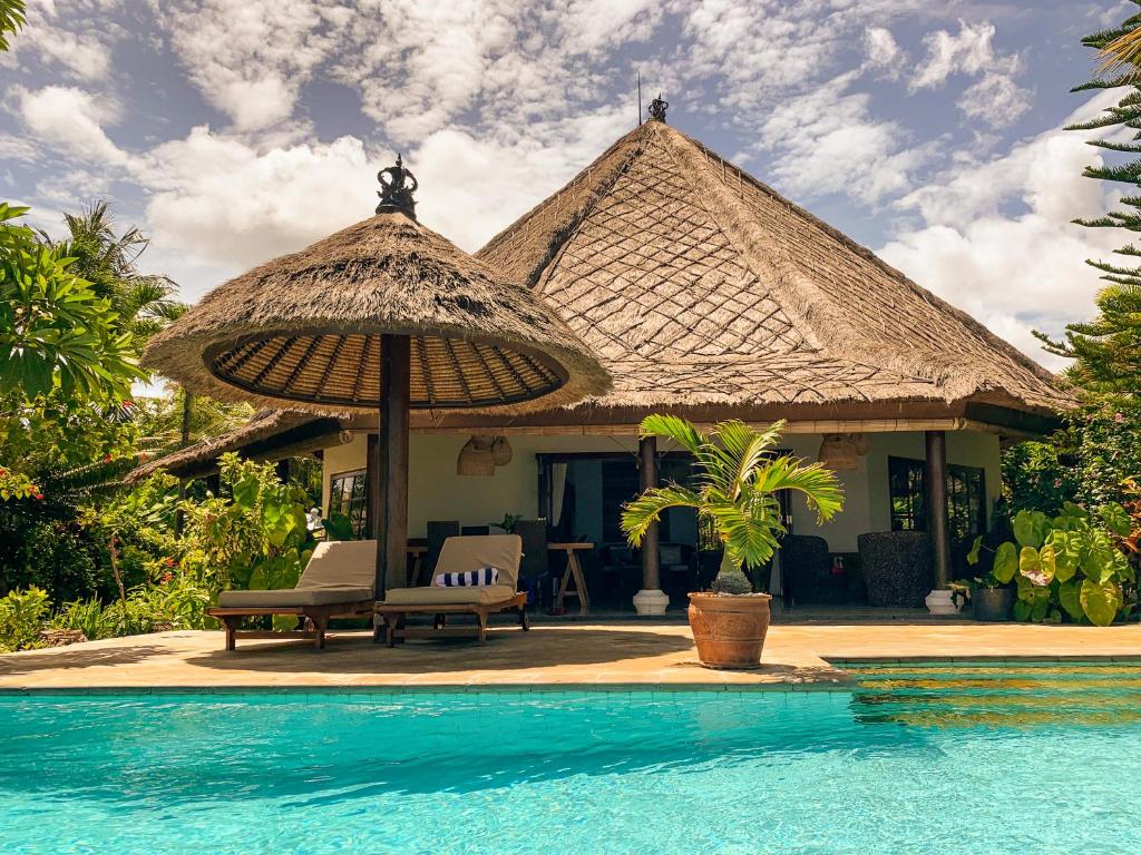 a house with an umbrella next to a swimming pool at Villa Cahaya - Bali Sea Villas Beachfront and private pool in Pengastulan