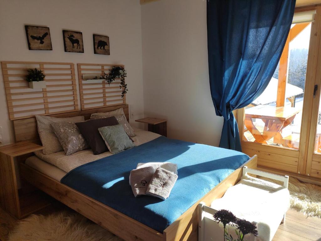 sypialnia z łóżkiem z niebieską pościelą i oknem w obiekcie Apartament Borowikowe Zacisze w mieście Falsztyn