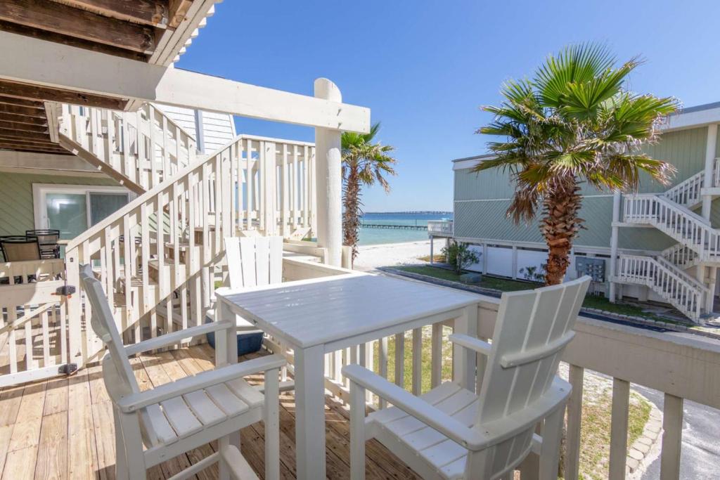 einen weißen Tisch und Stühle auf einer Terrasse mit Strand in der Unterkunft Boardwalk F10 in Pensacola Beach