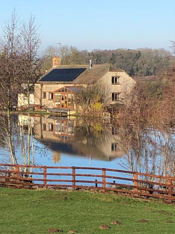 a large house sitting on top of a body of water at Astwell Mill in Helmdon