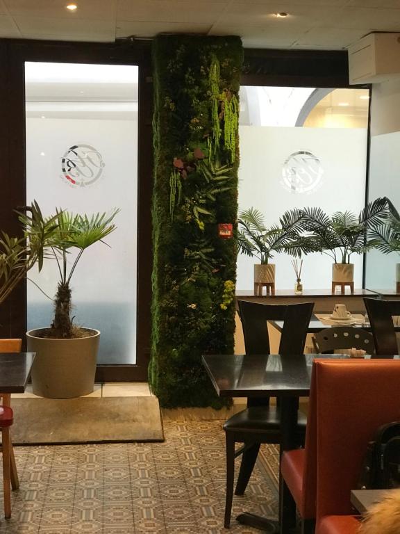 een restaurant met een tafel en planten in een kamer bij Hotel de Bretagne in Lyon