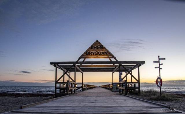 un paseo marítimo de madera que conduce a la playa con un cartel en Åhus Resort en Åhus