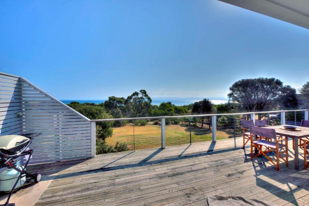 une terrasse en bois avec une table et des chaises. dans l'établissement Waders, à Coles Bay