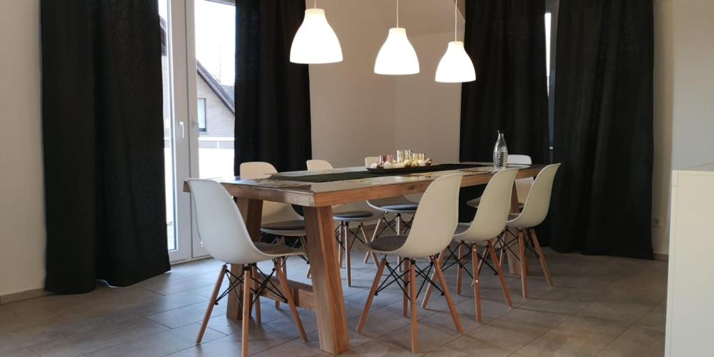 a dining room with a wooden table and white chairs at Modern Wohnen I Parkplatz I Wlan I Netflix I Balkon I 6 Schlafplätze in Bad Oeynhausen