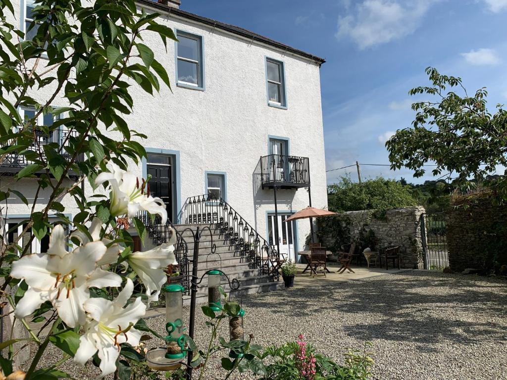 ein weißes Haus mit einem Zaun und weißen Blumen in der Unterkunft Riverbank House Bed and Breakfast Innishannon in Inishannon