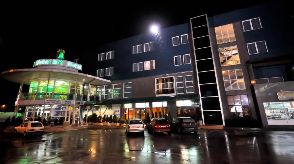 een gebouw met auto's geparkeerd op een parkeerplaats 's nachts bij Hotel BM in Sarajevo