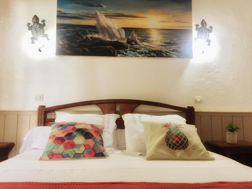 a bedroom with a bed with white sheets and pillows at Saint Leu - Chambre 3 épis avec PDJ piscine en pleine nature vue mer - Bardzour in Saint-Leu