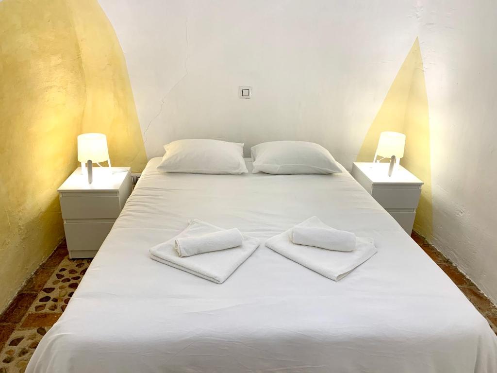 een wit bed met twee witte handdoeken erop bij Casa Cueva Castillo in Perales de Tajuña