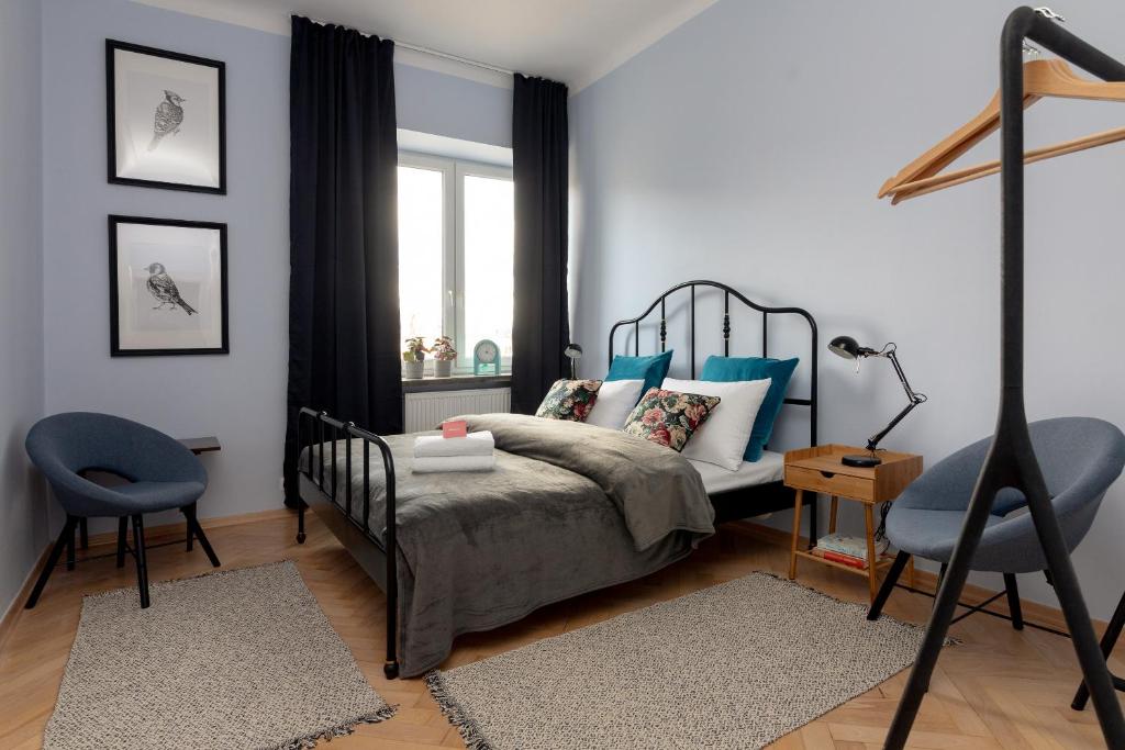 um quarto com uma cama e uma cadeira azul em Hala Mirowska Stylish Apartment em Varsóvia