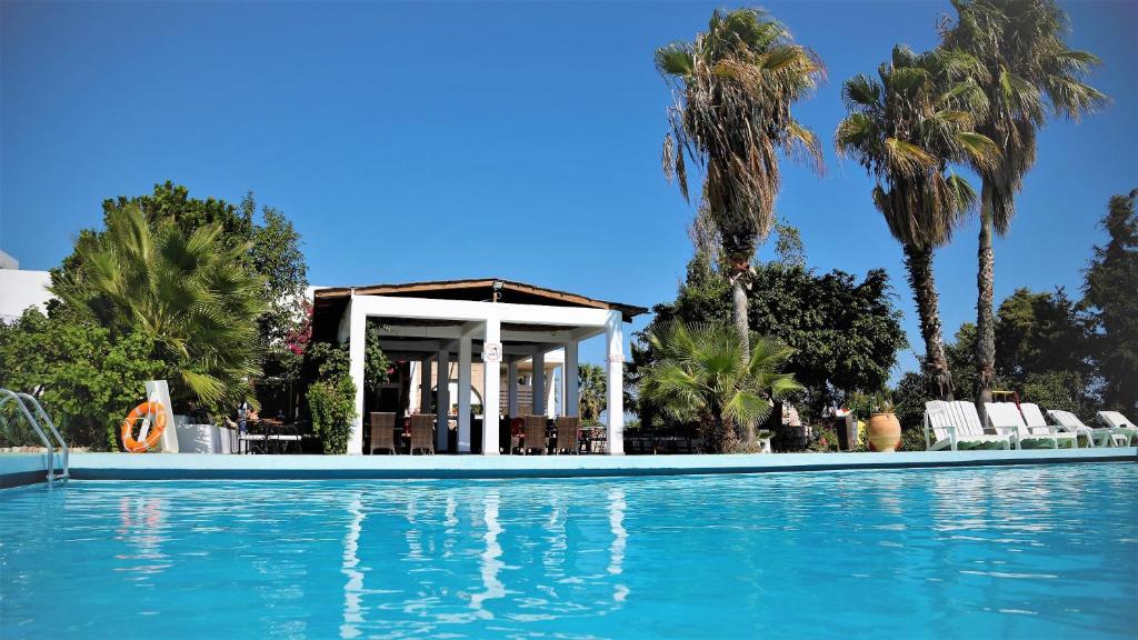 a swimming pool in front of a house with palm trees at Rhodian Sun Hotel in Paradeísion