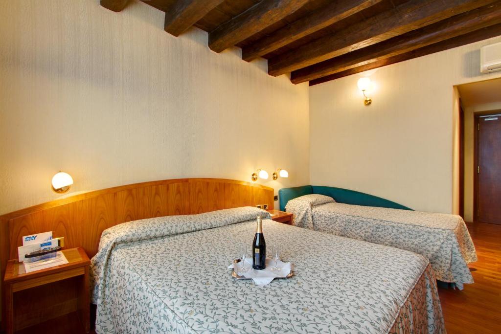 羅馬的住宿－柯羅酒店，一间卧室设有两张床,桌子上放着一瓶葡萄酒
