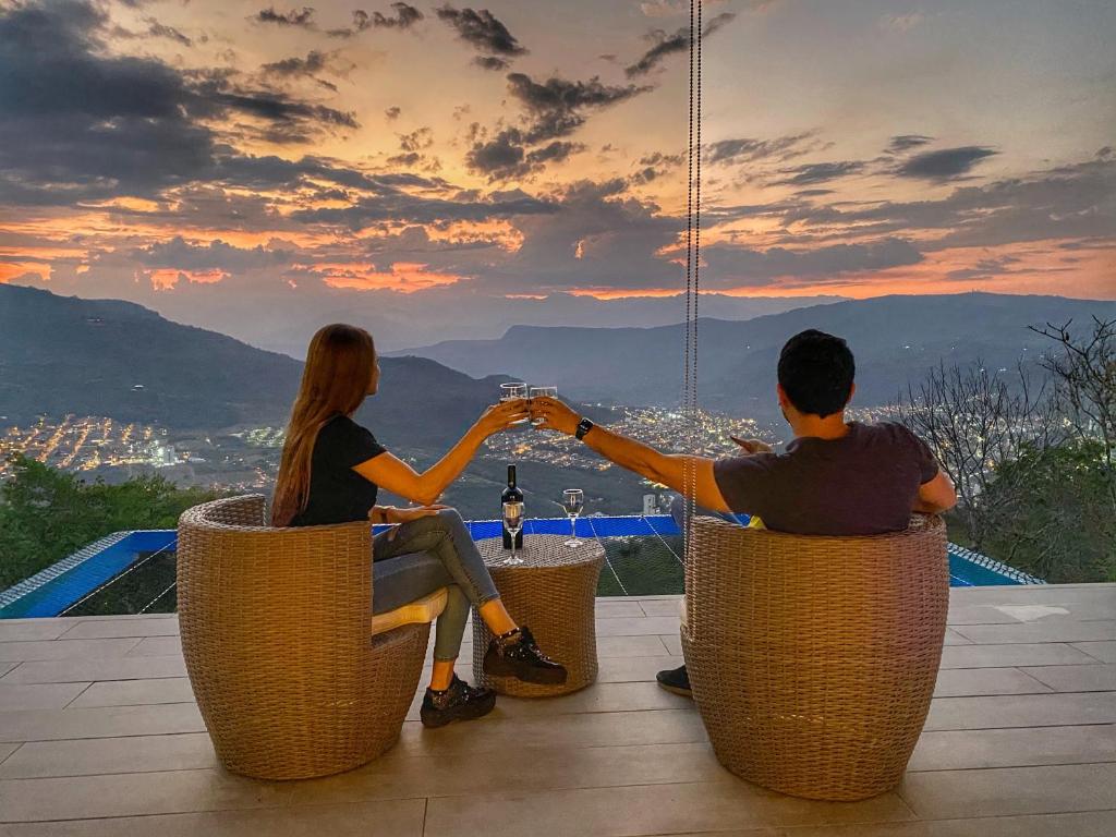una pareja sentada en sillas de mimbre viendo la puesta de sol en Sunset Palm Lodge, en San Gil