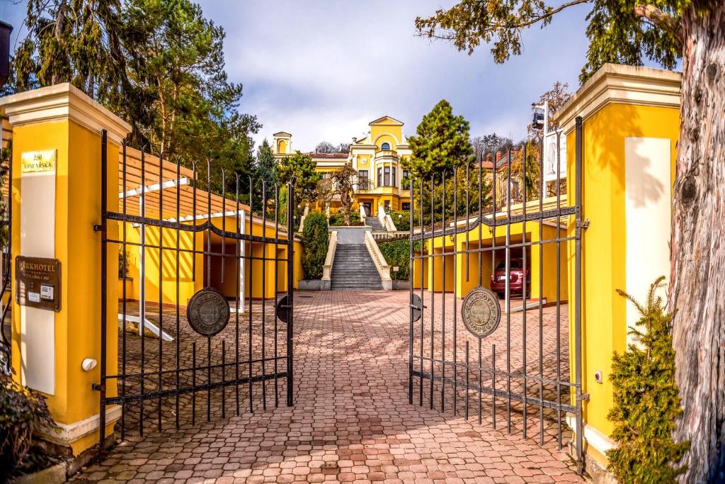 a gate in front of a yellow house with a driveway at Parkhotel Brno in Brno