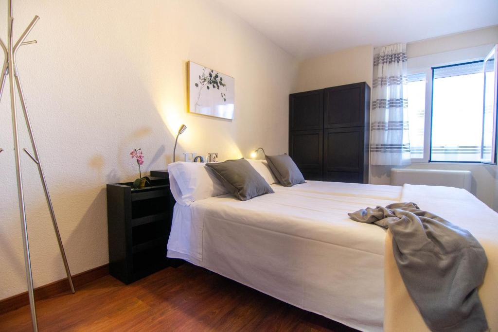 sypialnia z dużym łóżkiem z białą pościelą w obiekcie Apartamentos Centro Norte w Madrycie