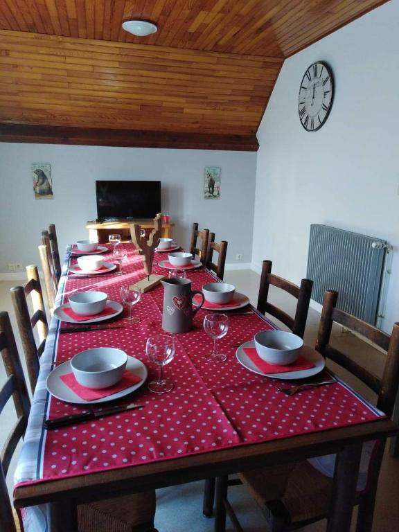 une table avec un tissu de table rouge, des chaises et une horloge dans l'établissement Location de la cascade 8 personnes, à Besse-et-Saint-Anastaise