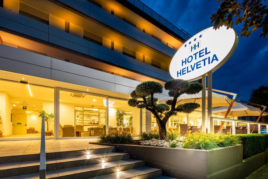 un cartello di benvenuto dell'hotel di fronte a un edificio di Hotel Helvetia a Lignano Sabbiadoro