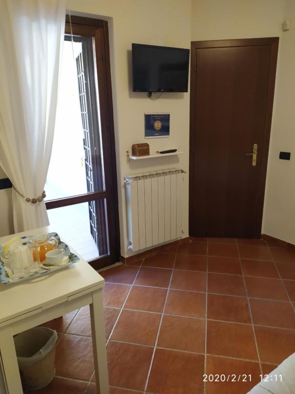 una camera con una porta e un pavimento piastrellato con un tavolo di L'Albicocco a Ladispoli