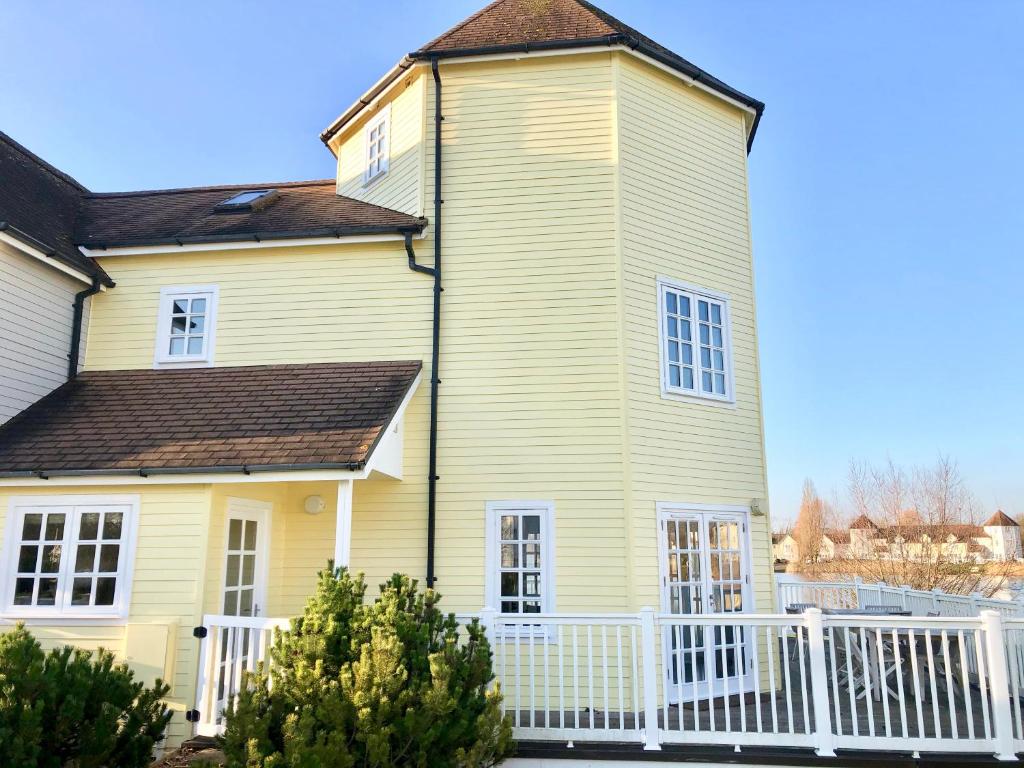 a yellow house with a white fence at Hello !! and welcome to Solius Lodge in South Cerney