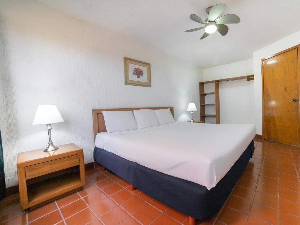 een slaapkamer met een groot wit bed en een lamp bij Hotel La Rinconada Santa Fe in Xochitepec