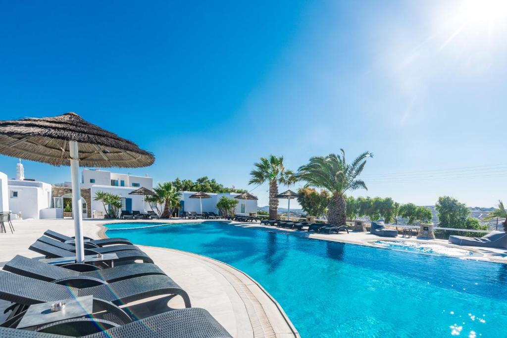 a swimming pool with chairs and an umbrella at Giannoulaki Hotel in Mikonos