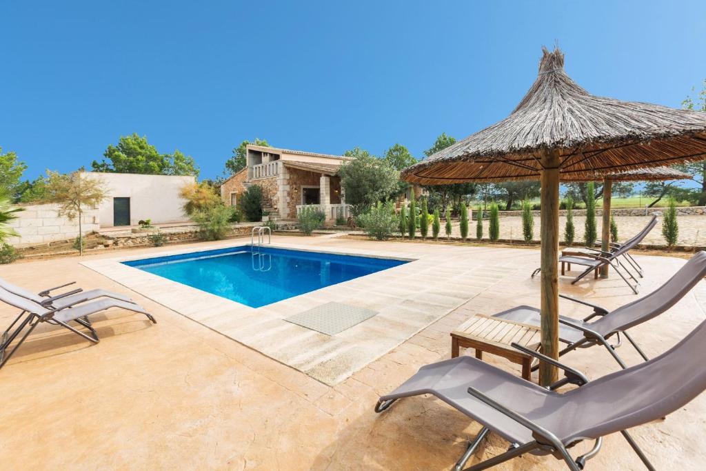 un patio con sillas, una sombrilla y una piscina en Sa Cunia en Campos