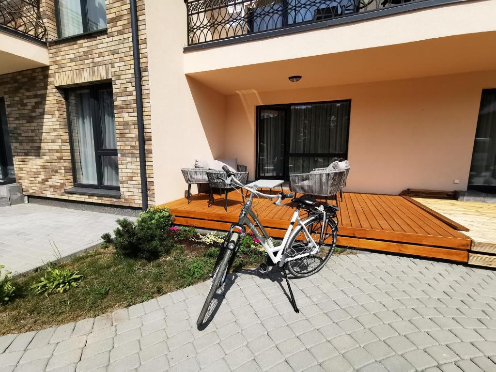 a bike parked in front of a house with a wooden deck at Scandinavian Apartment in Palanga in Palanga