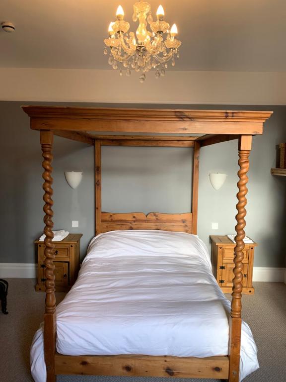 a bedroom with a wooden bed with a chandelier at Lansdown House Bed & Breakfast in Market Drayton