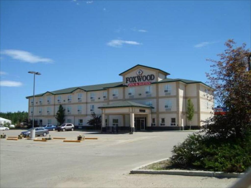 un grand bâtiment avec un parking en face de celui-ci dans l'établissement Foxwood Inn & Suites Drayton Valley, à Drayton Valley