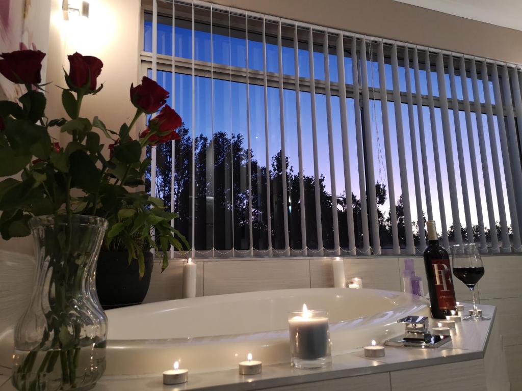 a white bath tub with a vase of roses and candles at Diamond House Guesthouse in Cape Town