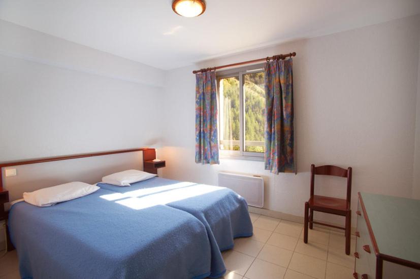 a bedroom with a blue bed and a window at Gîtes du Presbytère in Saint-Dalmas-le-Selvage