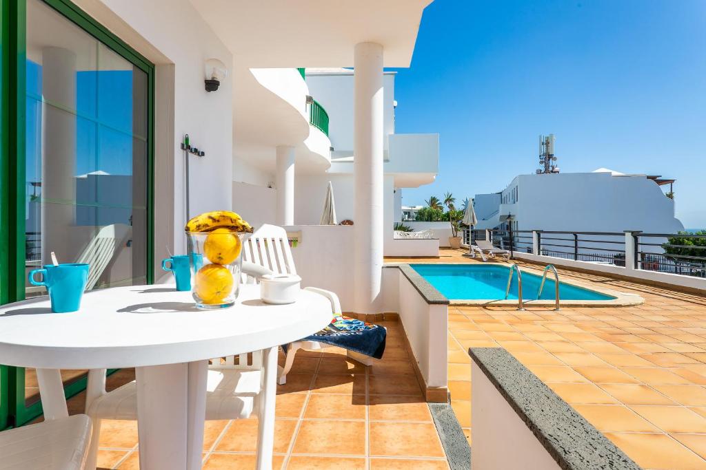 una mesa blanca y sillas en un balcón con piscina en Apartamentos los Quiqueres, en Puerto del Carmen