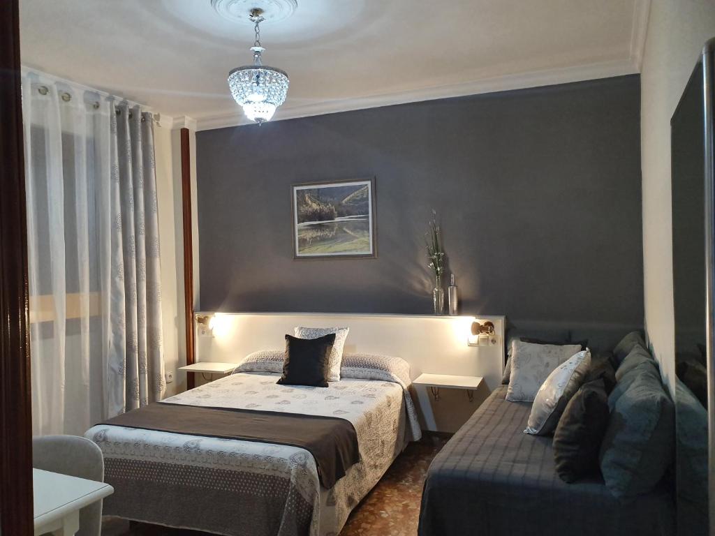 a hotel room with two beds and a couch at LUNA-Guest Rooms in Alcalá de Guadaira