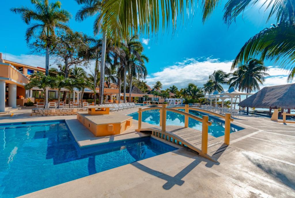 
a beach with a pool, chairs, and a pool table at Puerto Aventuras Hotel & Beach Club in Puerto Aventuras
