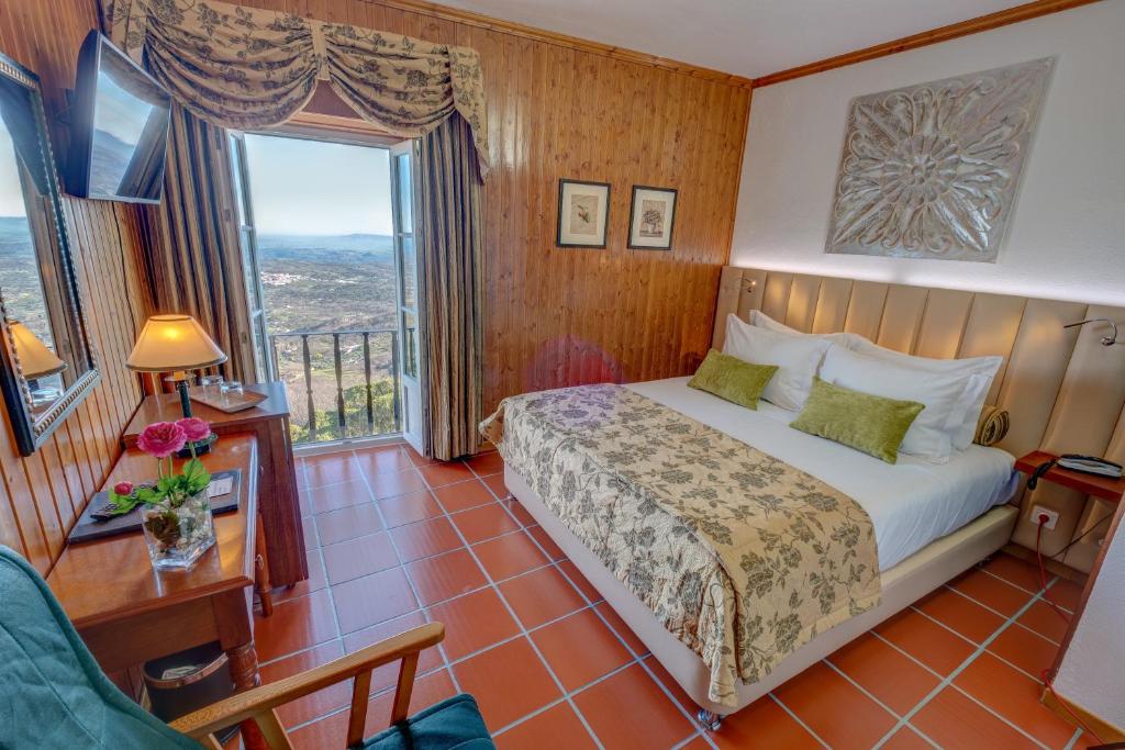 ein Schlafzimmer mit einem Bett und einem großen Fenster in der Unterkunft El-Rei Dom Manuel Hotel in Marvão