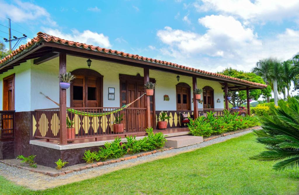 a house with a porch and a green yard at Finca Rionegro Rancho La Soledad in Montenegro