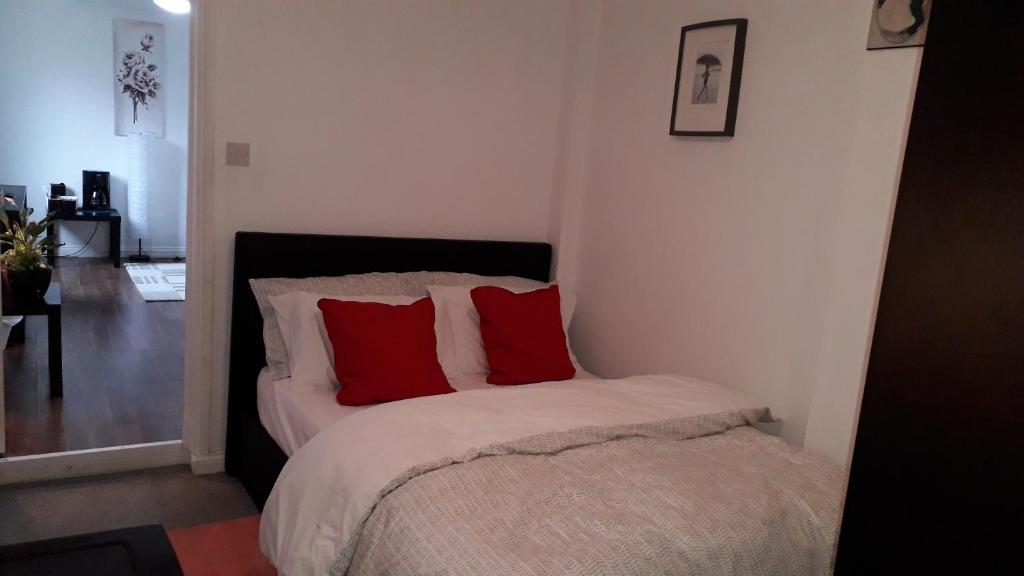 a bedroom with a bed with two red pillows at Cosy London holiday Home (Near O2 arena) in London