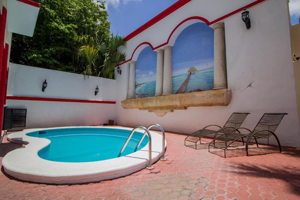 a swimming pool with chairs next to a building at Hotel El Español Centro Historico in Mérida