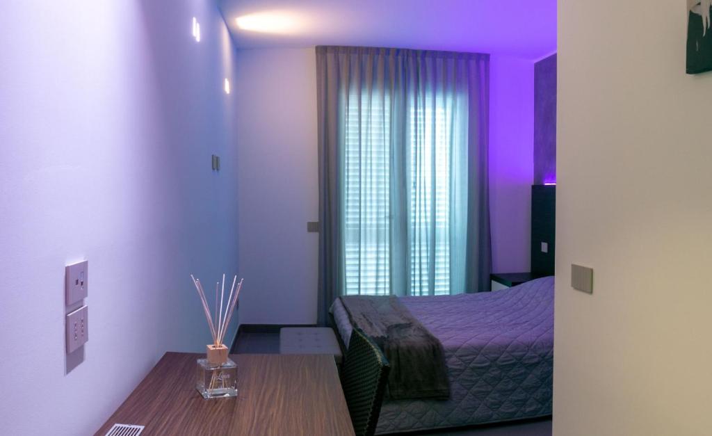 ein Schlafzimmer mit violetter Beleuchtung und ein Bett mit einem Tisch in der Unterkunft BRIGANTE SUITES in Misano Adriatico