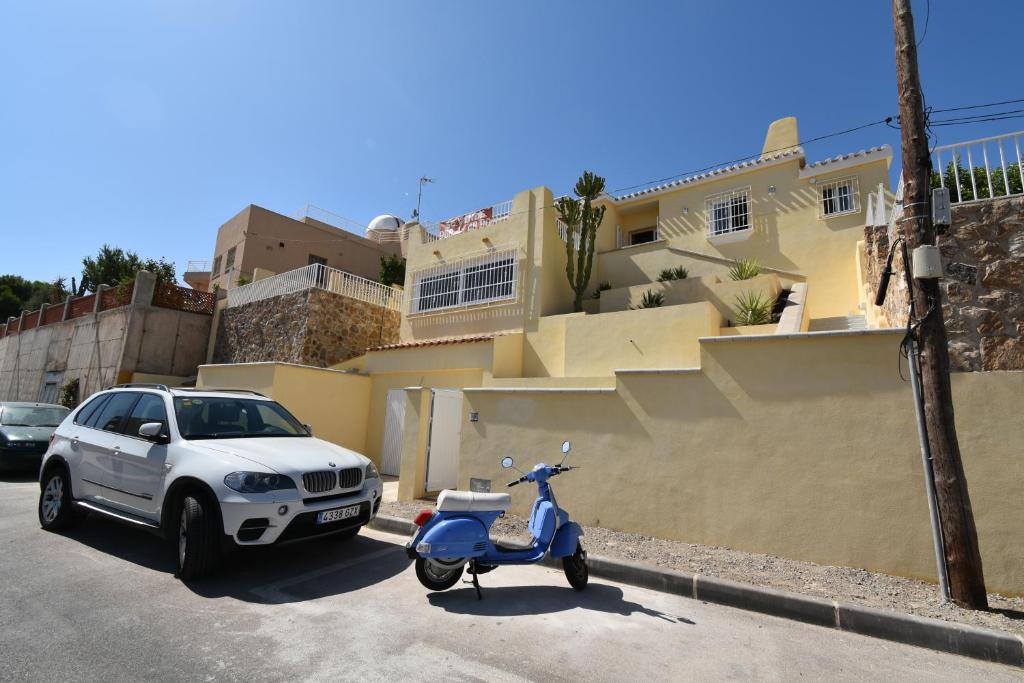 Villa Bonita en Aguilas Murcia con piscina privada في أغيلاس: سيارة وسكوتر متوقفة أمام منزل