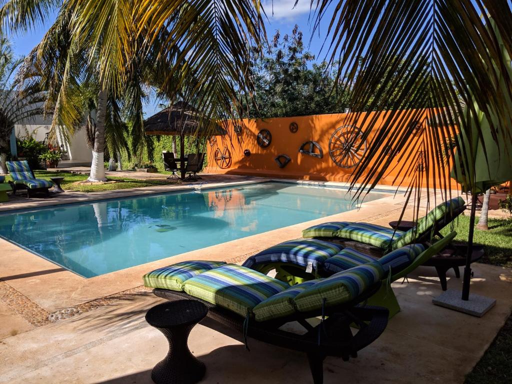 a swimming pool with lounge chairs and a hammock next to it at Casa Xcanatun in Mérida