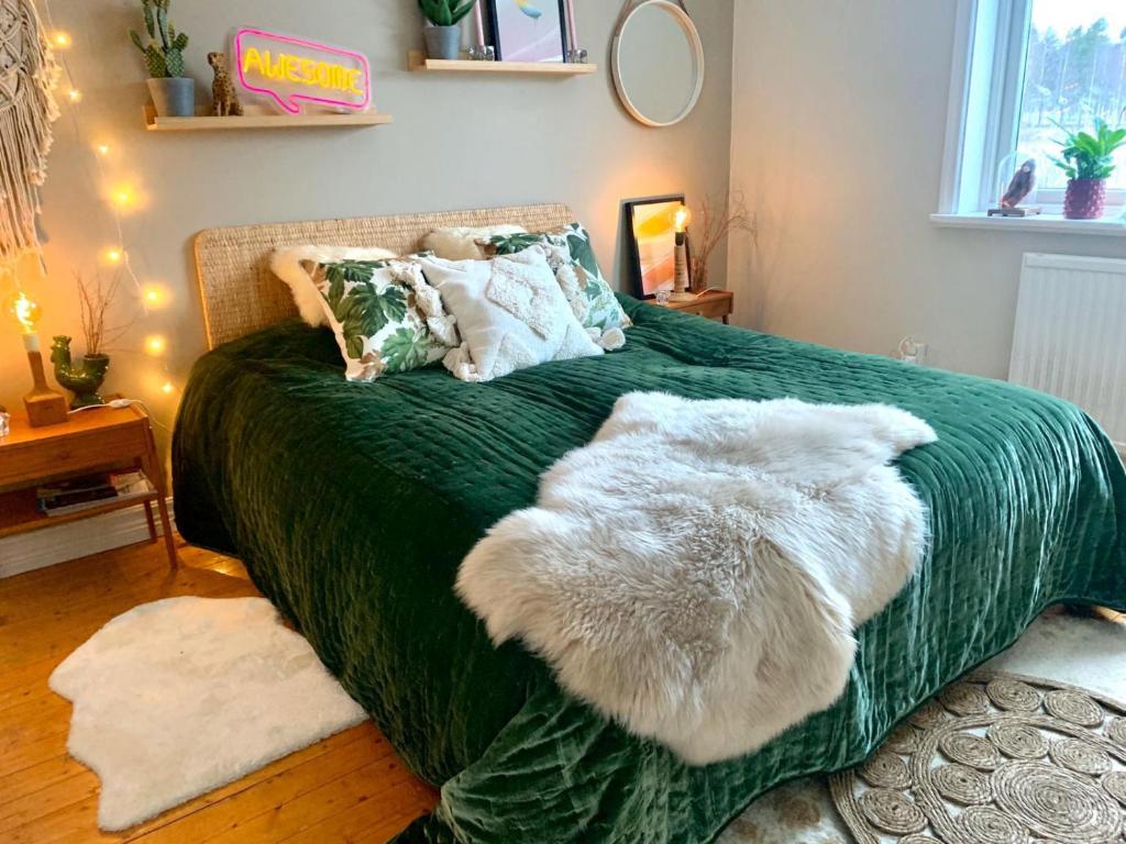 um quarto com uma cama verde e 2 almofadas brancas peludas em Super cosy cottage in heart of Dalarna em Västra Fors