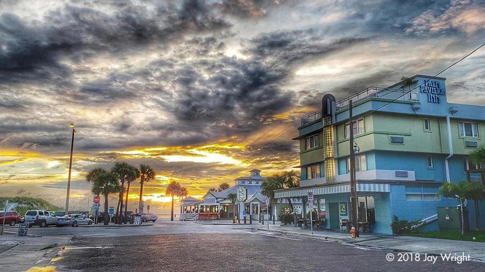 a building on the side of a street with a sunset at Palm Pavilion Inn in Clearwater Beach