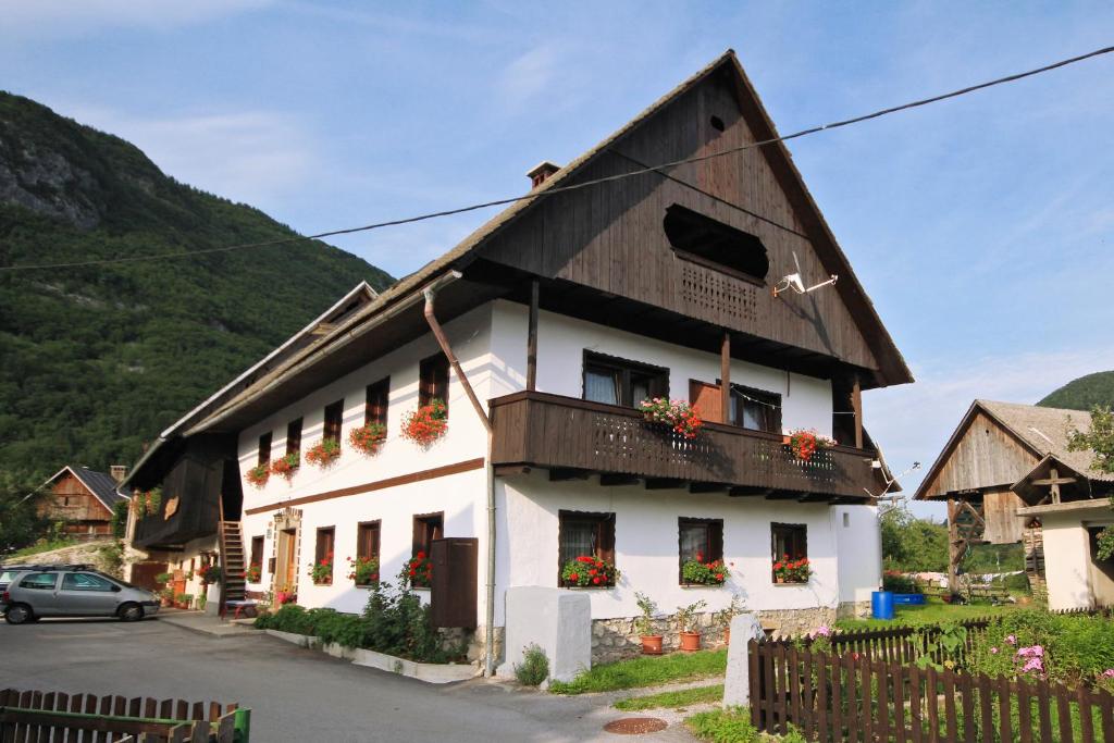 a white building with a black roof and flowers on the windows at Rooms Pekovec Bohinj in Bohinj