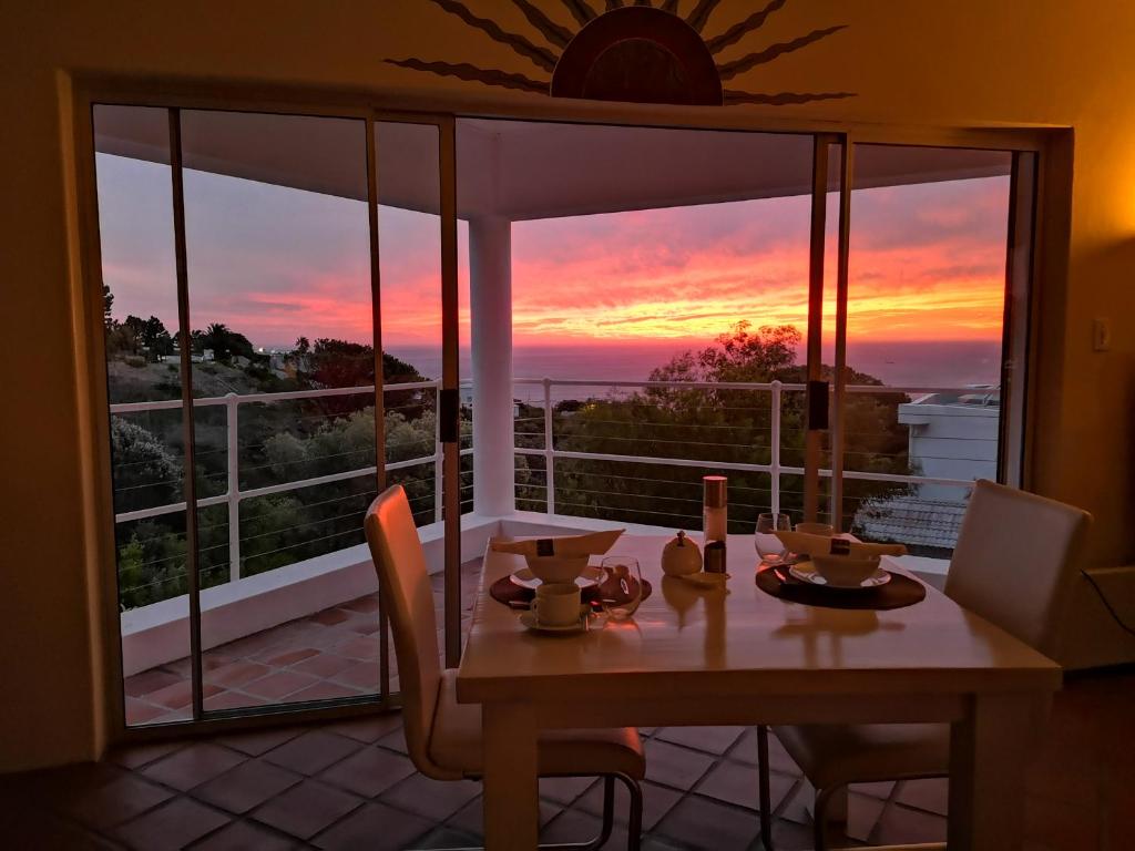 a dining room table with a view of the sunset at Diamond House Guesthouse in Cape Town
