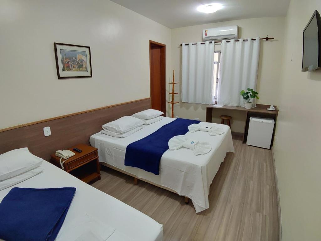 um quarto de hotel com duas camas e uma janela em Hotel Orleans em Petrópolis