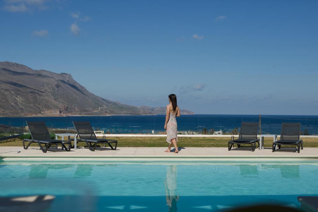 a woman is standing next to a swimming pool at Larimar Luxury Sea View Villa in Kissamos